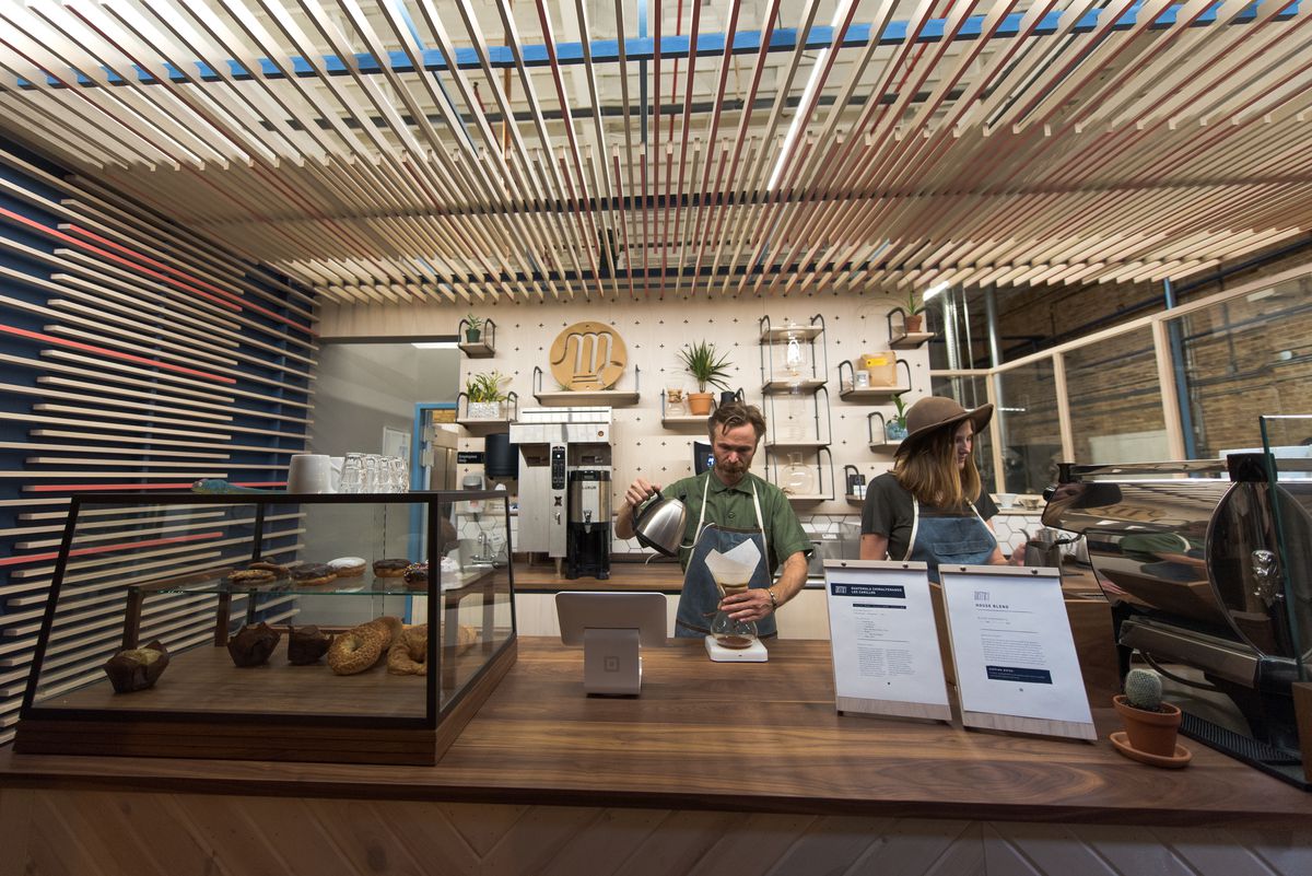 A barista creates a pour-over splash behind a opposite during a cafe.